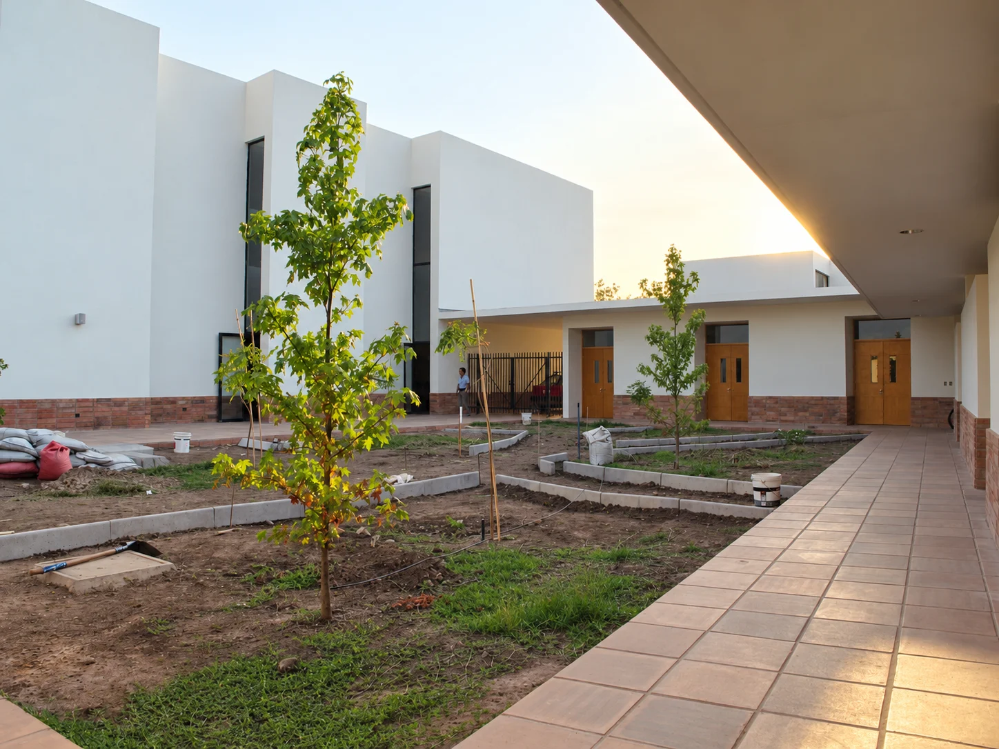 El patio de la parroquia, con árboles jóvenes y un corredor que conecta sus espacios